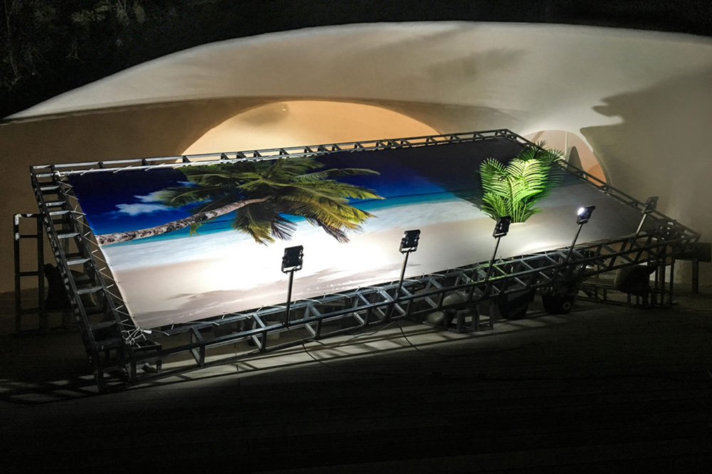 An artwork resembling a large billboard with a tropical beach and palm trees