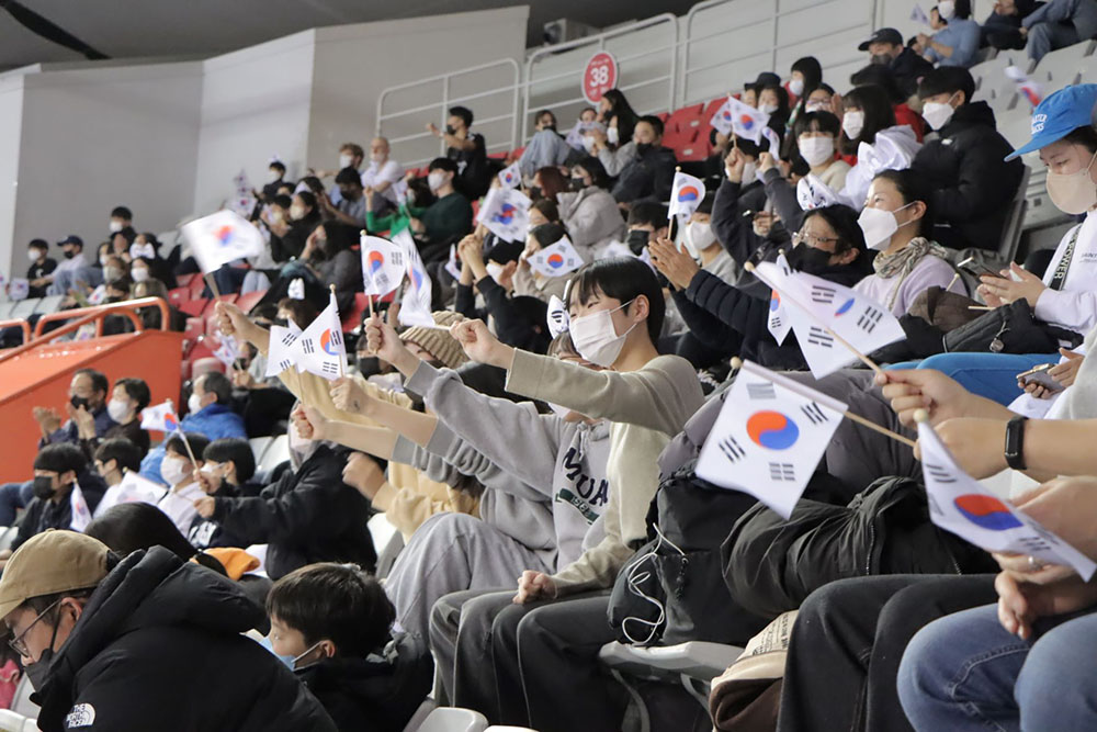 People in a stadium waving Korean flags