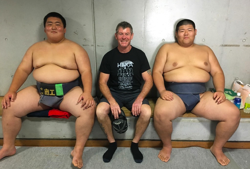 A New Zealand man sitting in between two young sumo wrestlers