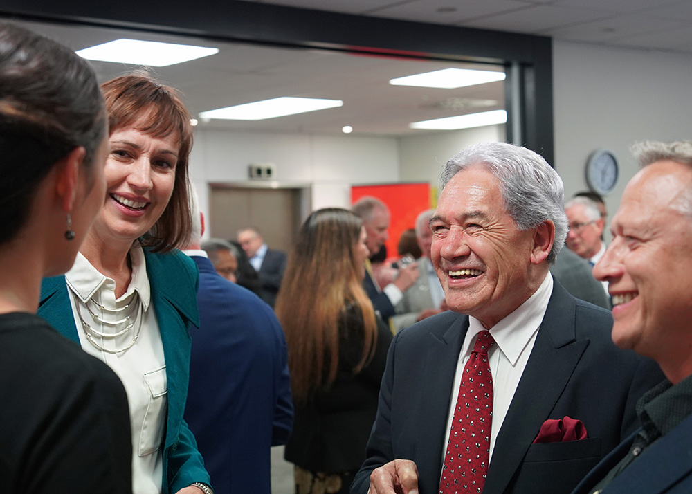 Suz Jessep and Winston Peters talking to someone in a crowded room