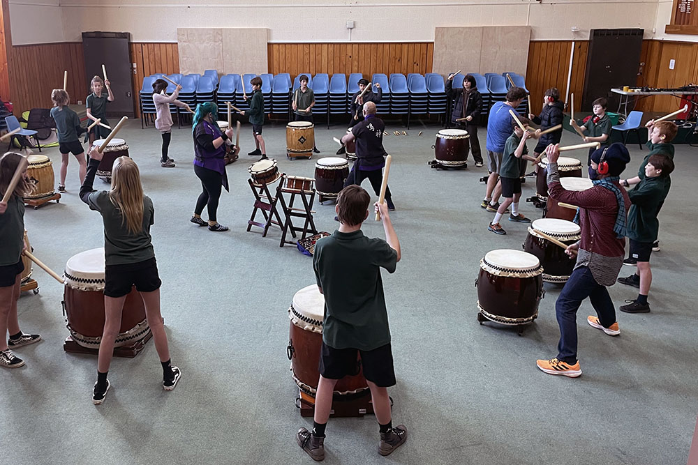A group of students in a hall playing taiko drums