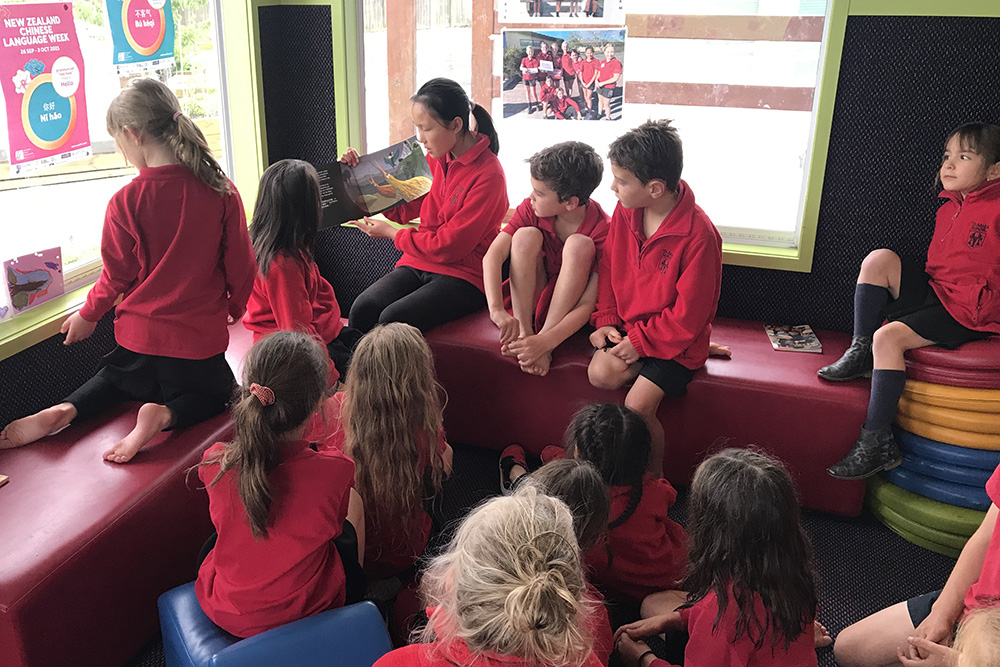 A students reads Ruru's Hāngī to younger students