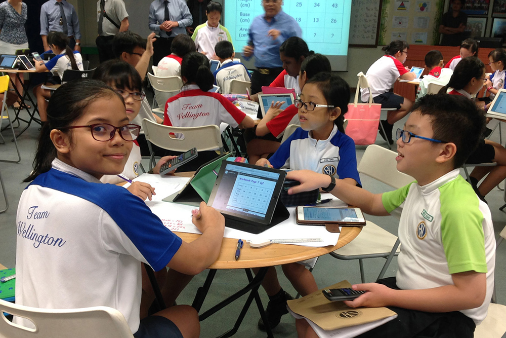 Three kids sitting at a table in class in Singapore