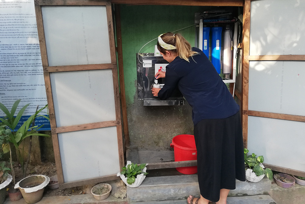 Jo filling a cup from a brand new filter in Korail slum