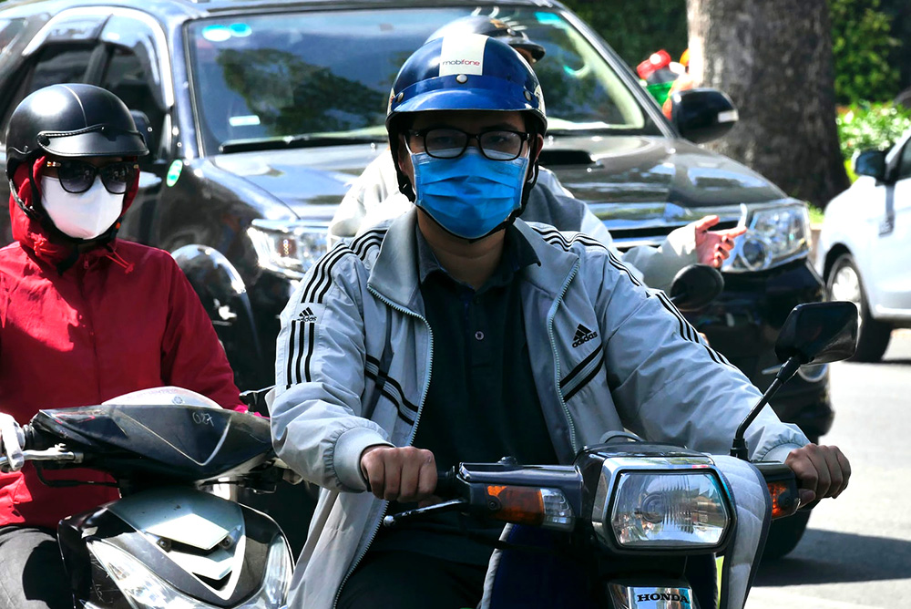 A man on a motor scooter wearing a mask