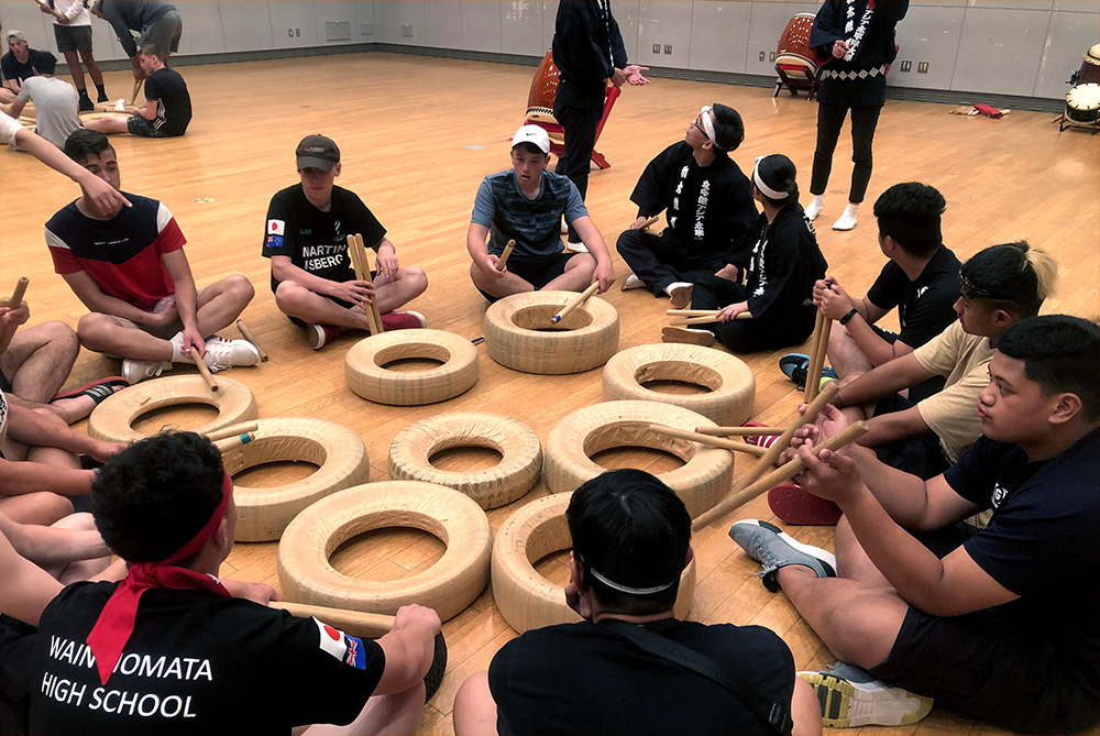 The Wainuiomata students sitting in a circle to practice drumming on tyres