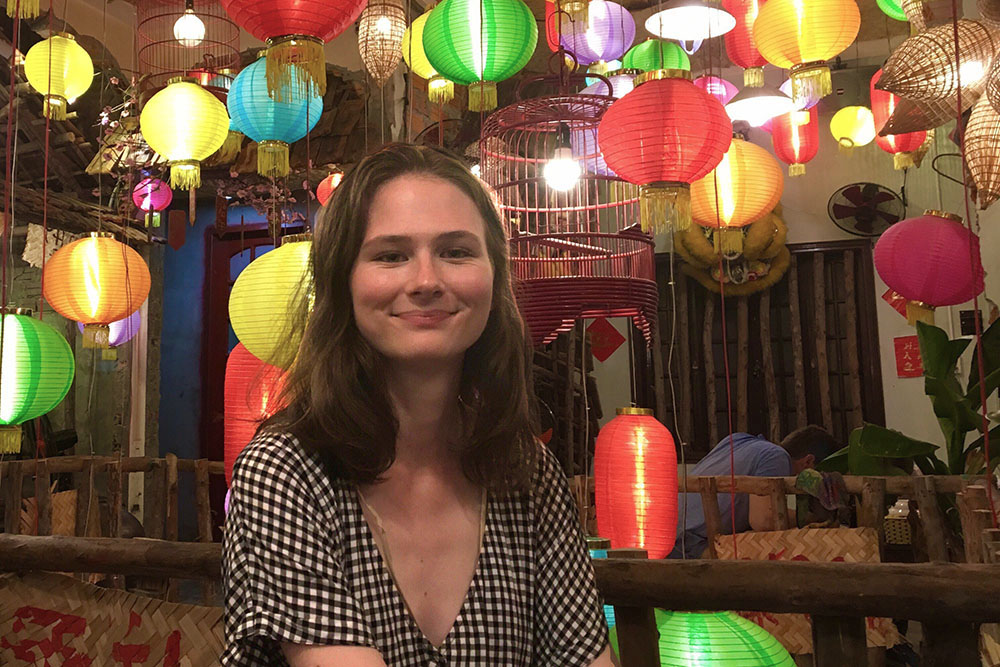 Abby sitting in a room full of colourful lanterns
