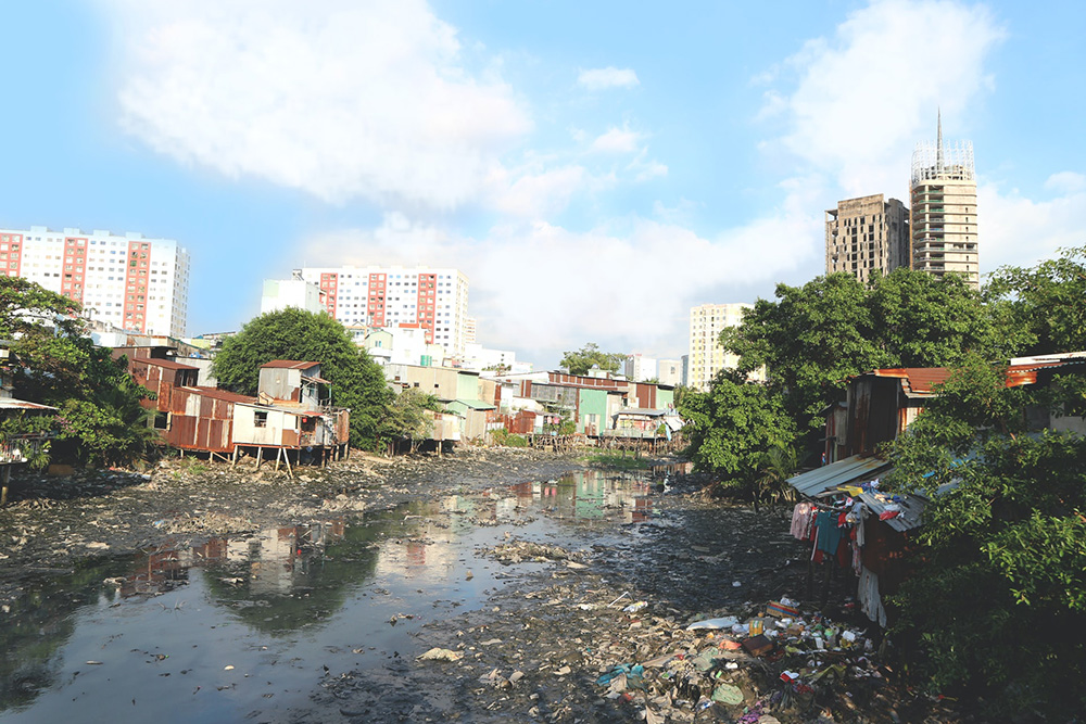 A polluted city waterway with shacks on its banks 