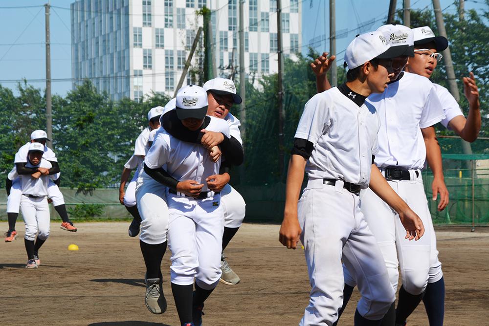 Young baseball players piggy-backing each other at training 
