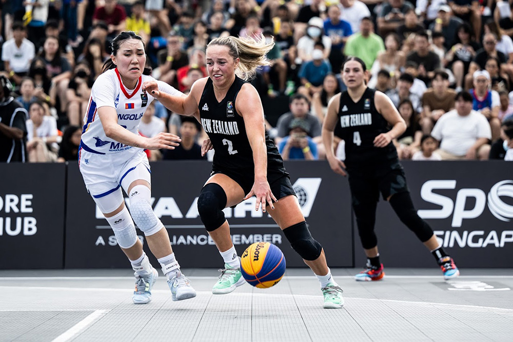 A Tall Ferns player with the ball trying to get past another player on the basketball court