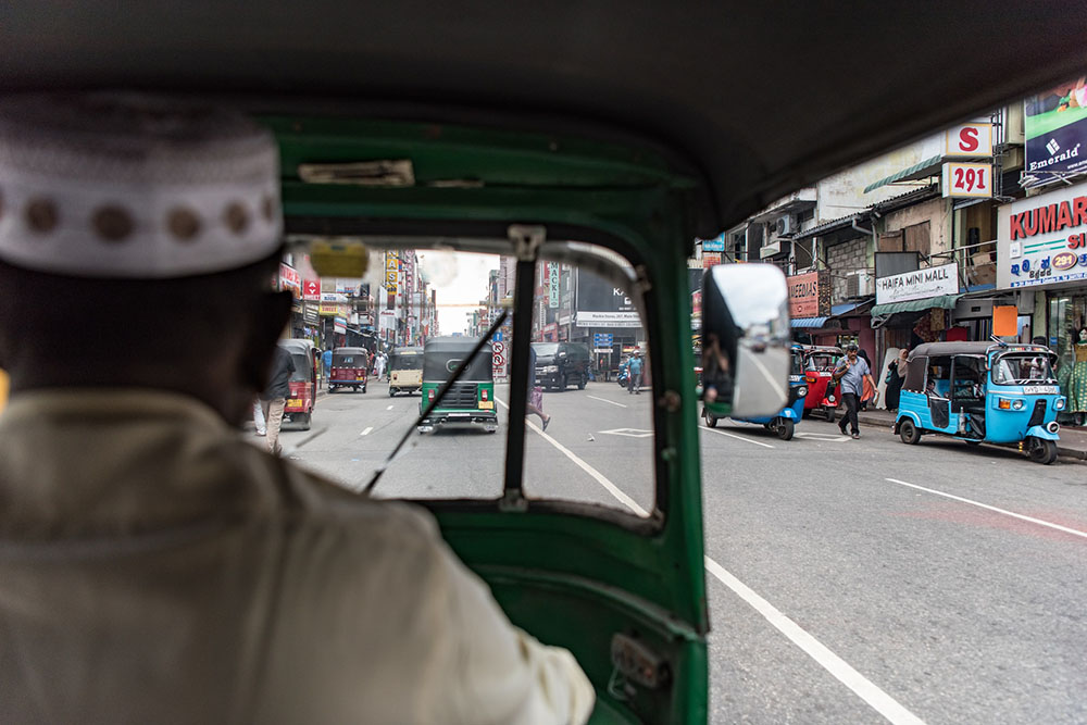 A shot from a tuktuk looking at the back of the driver's head and the road ahead