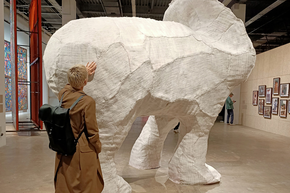 A woman touching a large elephantine sculpture