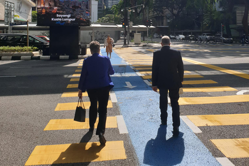 Dame Fran Wilde and David Capie crossing a large road in Kuala Lumpur