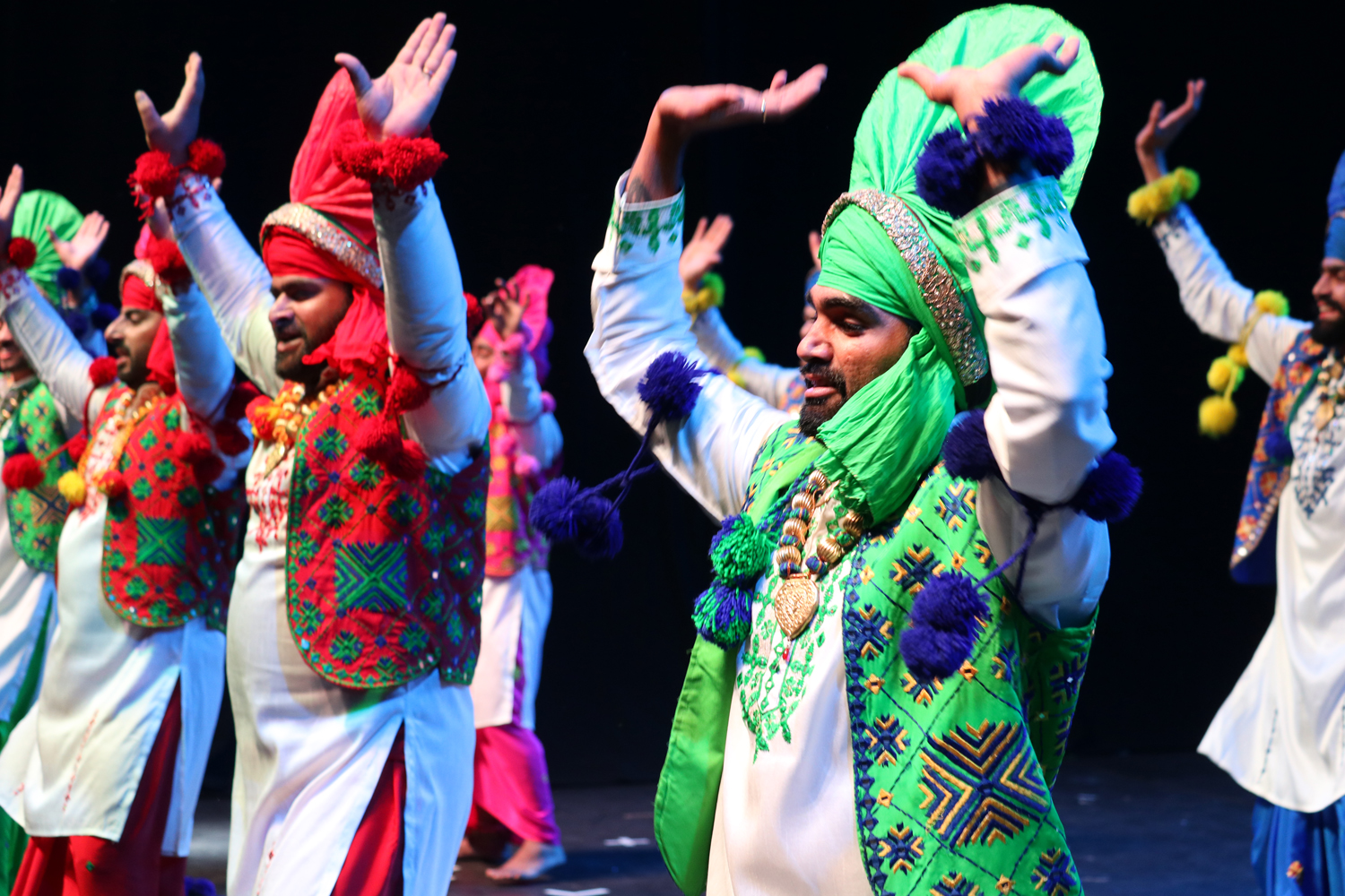 Men in colourful traditional Indian outfits dancing on stage