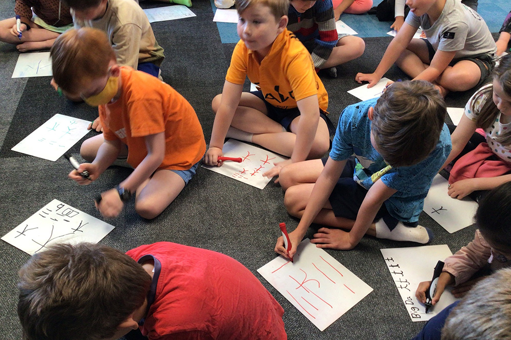 Students from Lucknow School students in Havelock North sitting on the floor practicing writing Chinese characters