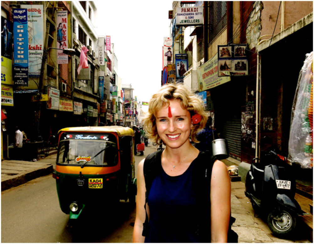 Journalist Isobel Ewing in a street in Bangalore with a tuktuk beside her