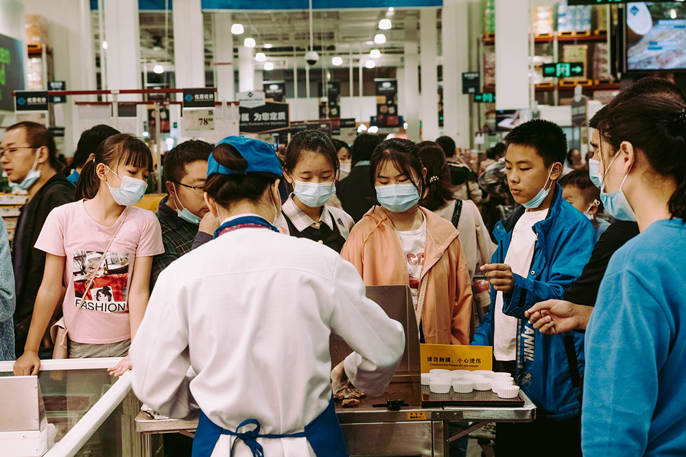 A group of people wearing masks waiting to buy dumplings