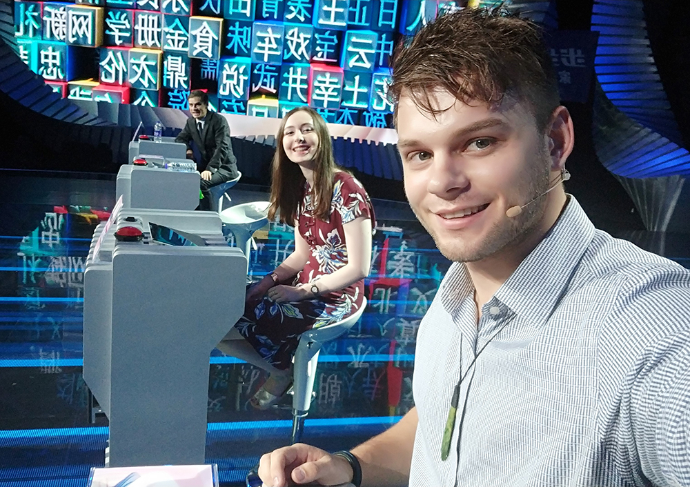 Nathan taking a selfie on the set of a Chinese TV show, with two fellow Chinese language contestants in the background