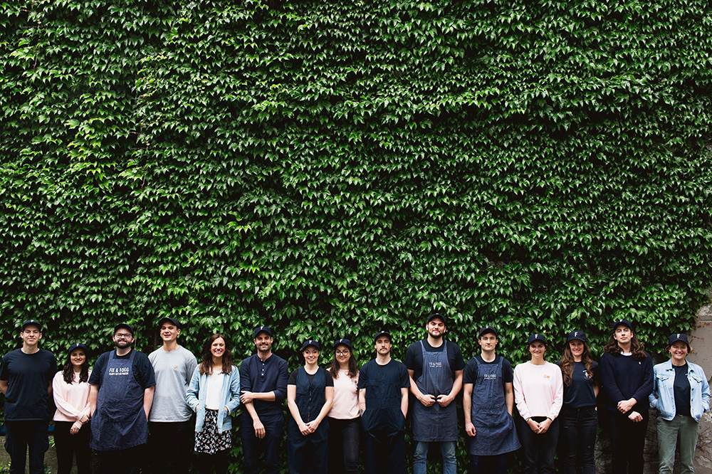 Fix and Fogg staff standing in a row in front of a large, ivy-covered wall