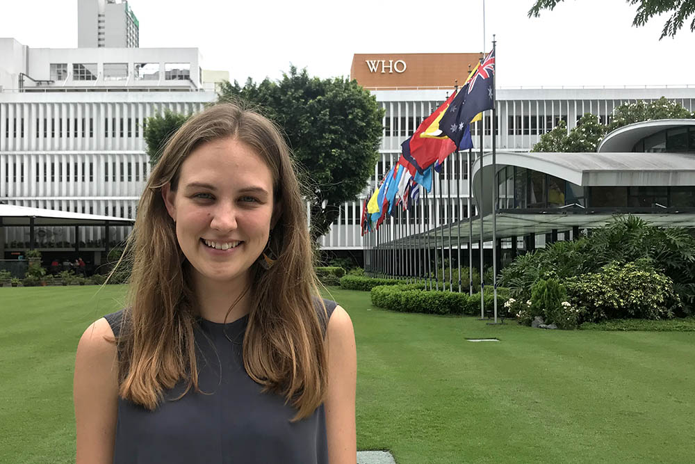 Sophia standing next to a row of national flags outside the WHO offices in Manila 
