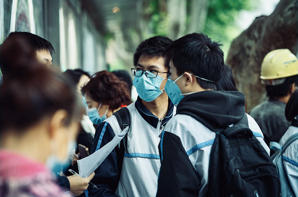 A small group of students milling around wearing face masks