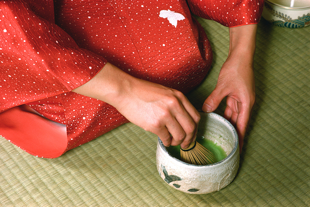 A woman mixing powdered green tea in a small bowl